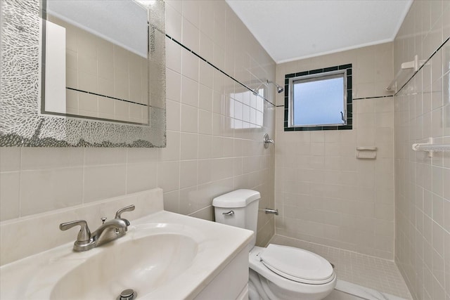 bathroom with toilet, tile walls, tiled shower, and vanity