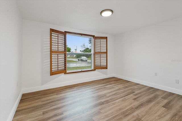 spare room featuring baseboards and wood finished floors