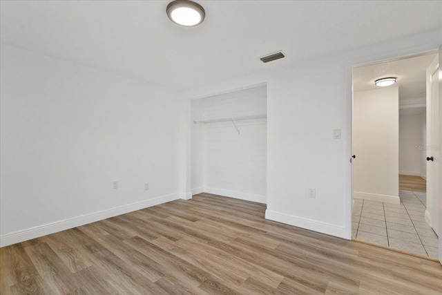 unfurnished bedroom with a closet, light wood-type flooring, visible vents, and baseboards