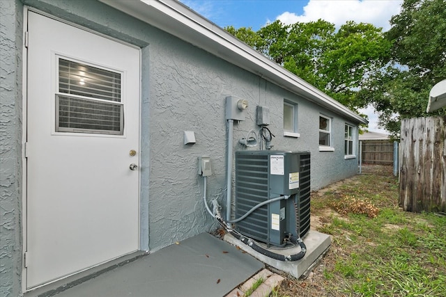 exterior space with central AC, fence, electric meter, and stucco siding