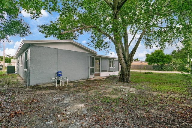 back of property featuring a sunroom, fence, and stucco siding