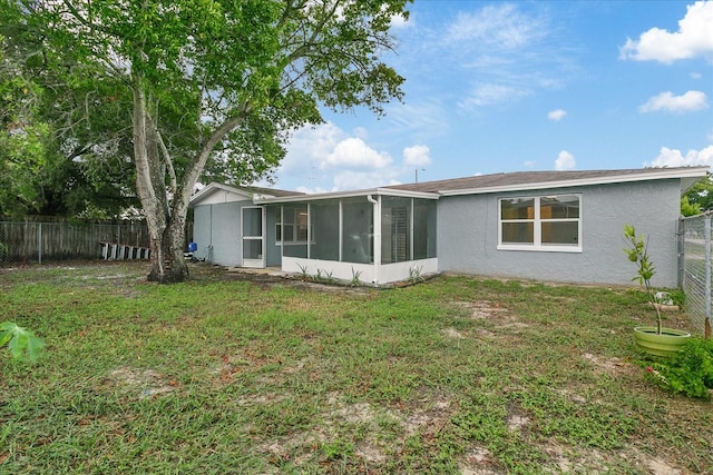 back of house with a yard, a fenced backyard, a sunroom, and stucco siding