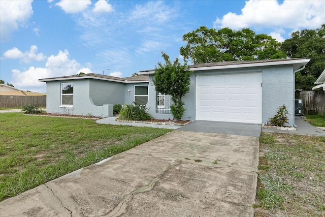 ranch-style house featuring concrete driveway, an attached garage, fence, a front lawn, and stucco siding