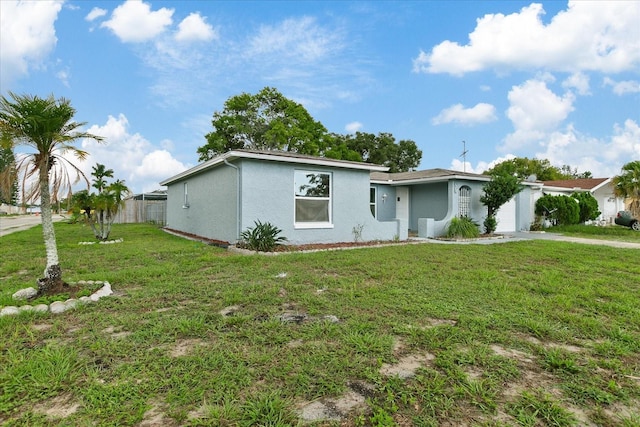 view of front of home featuring a garage, fence, driveway, stucco siding, and a front yard