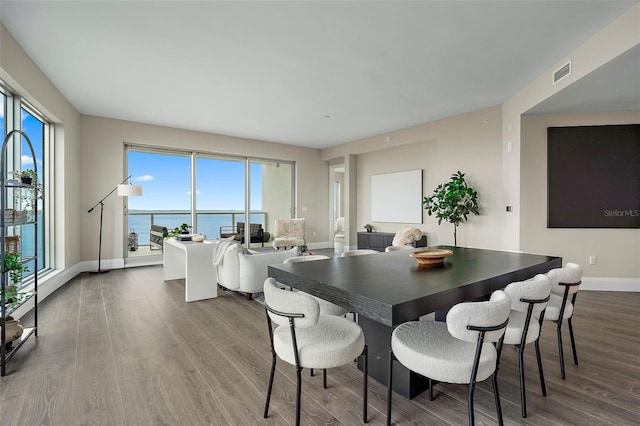 dining room with hardwood / wood-style flooring and a water view