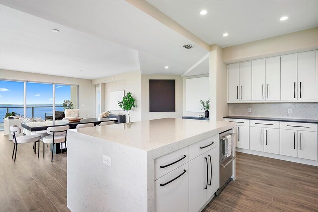 kitchen with white cabinetry, a center island, dark hardwood / wood-style flooring, and a water view