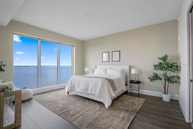 bedroom with a water view and dark hardwood / wood-style floors