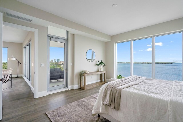 bedroom featuring a water view, dark hardwood / wood-style flooring, and access to exterior