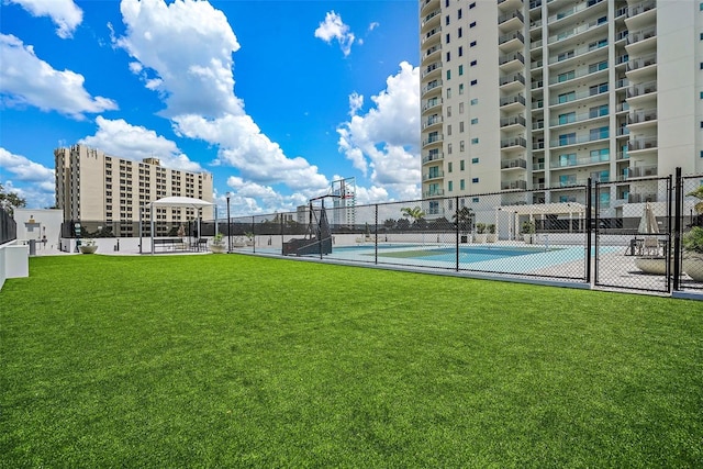 exterior space featuring basketball hoop, a yard, and tennis court