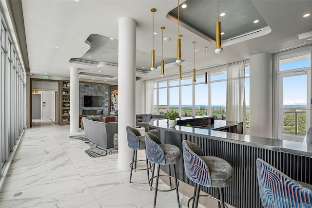 kitchen with a tray ceiling, a breakfast bar, and hanging light fixtures