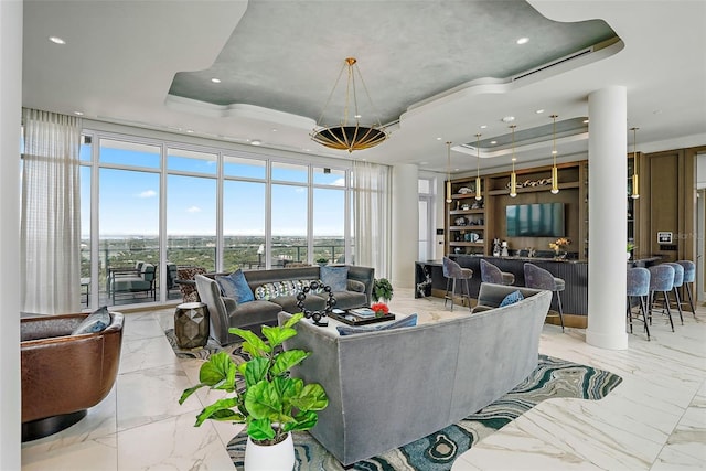 living room featuring a wall of windows, a tray ceiling, and plenty of natural light