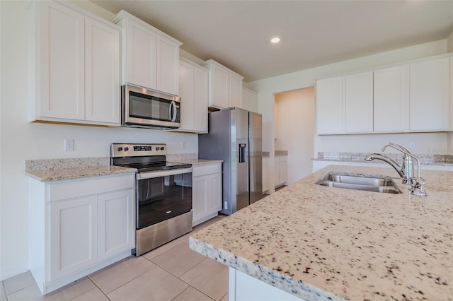 kitchen featuring sink, light tile patterned floors, appliances with stainless steel finishes, and white cabinets