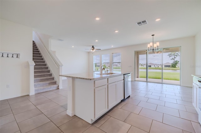 kitchen featuring pendant lighting, ceiling fan with notable chandelier, white cabinetry, a center island with sink, and stainless steel dishwasher