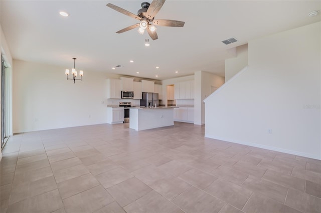 unfurnished living room with ceiling fan with notable chandelier and light tile patterned flooring