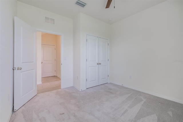 unfurnished bedroom featuring light carpet, ceiling fan, and a closet