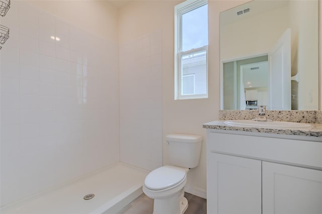 bathroom featuring vanity, toilet, and tiled shower