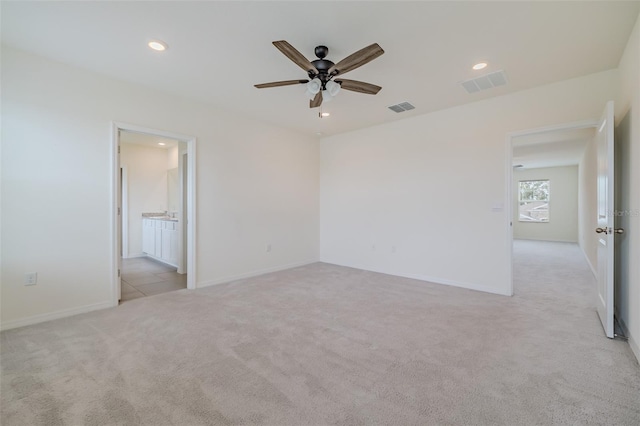 unfurnished bedroom featuring ensuite bath, light colored carpet, and ceiling fan