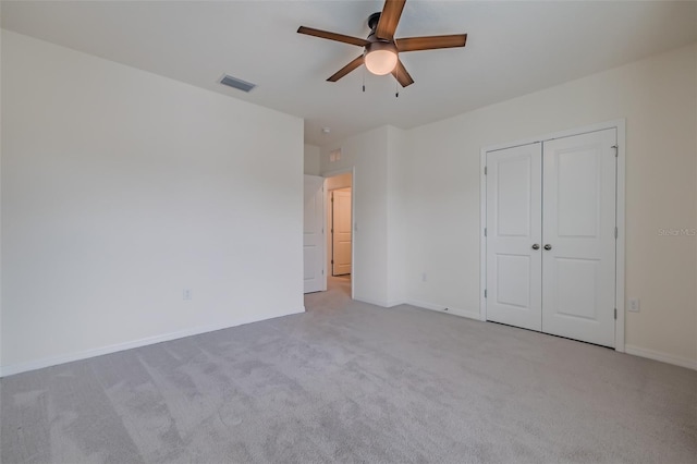 unfurnished bedroom with light colored carpet, ceiling fan, and a closet