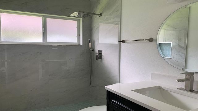 bathroom with tiled shower, vanity, and toilet