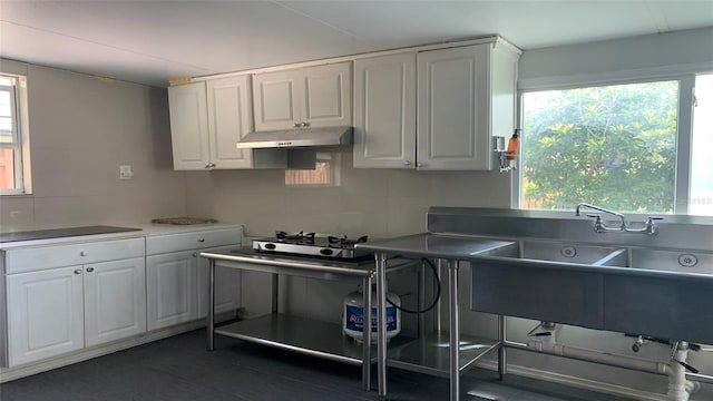 kitchen with stainless steel gas stovetop, sink, and white cabinets