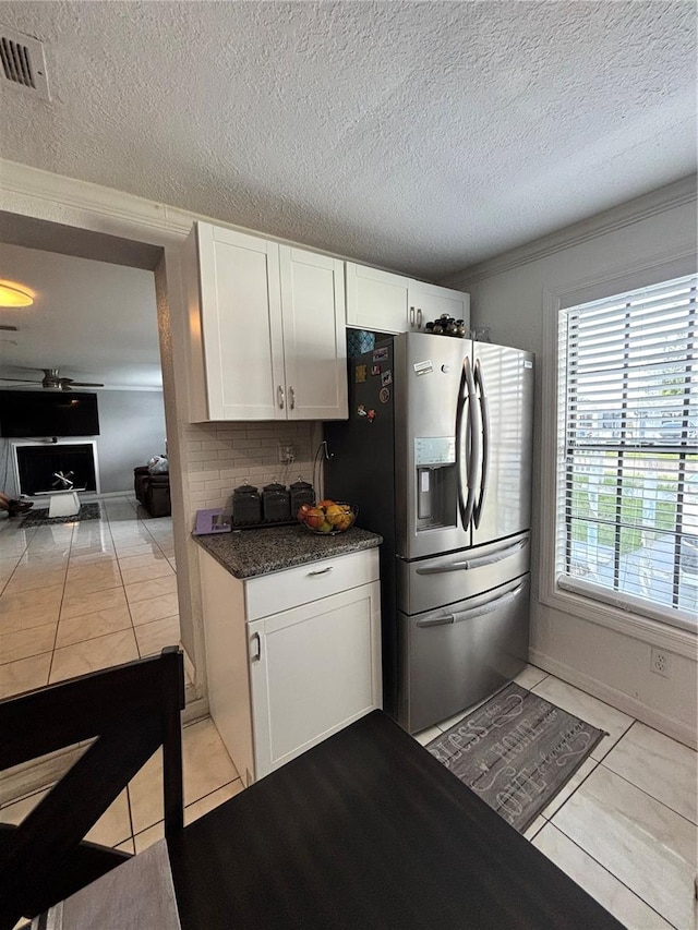 kitchen with a textured ceiling, light tile patterned flooring, stainless steel fridge with ice dispenser, and white cabinets