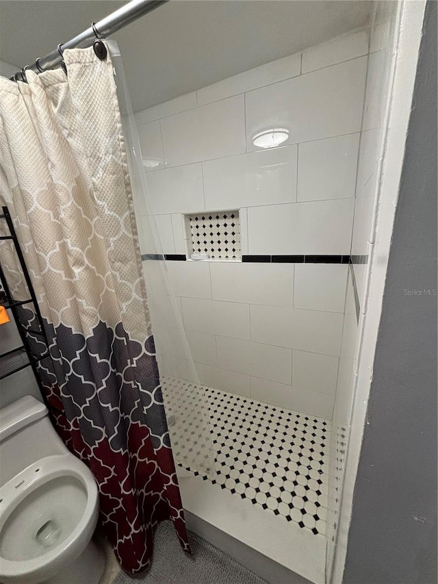 bathroom featuring toilet and curtained shower