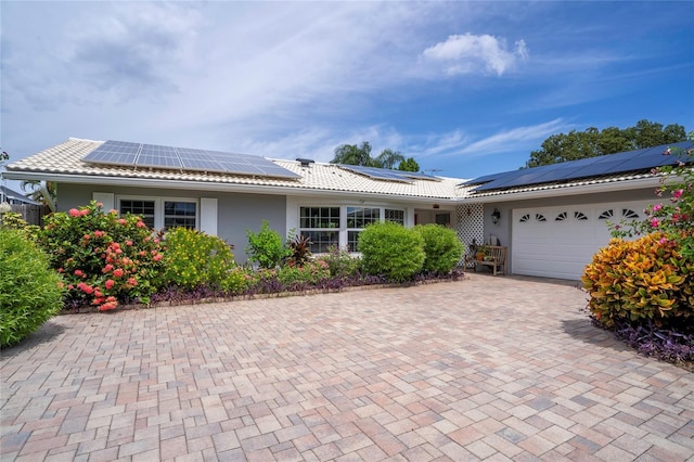 single story home featuring solar panels and a garage