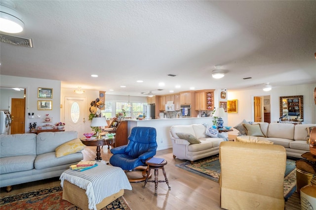 living room featuring a textured ceiling and light wood-type flooring