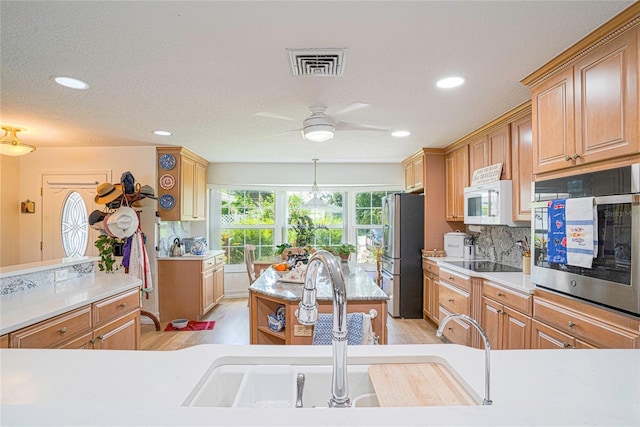 kitchen featuring visible vents, light wood-style flooring, a sink, appliances with stainless steel finishes, and a center island