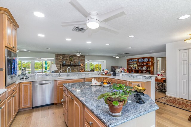 kitchen with appliances with stainless steel finishes, a kitchen island, kitchen peninsula, and ceiling fan