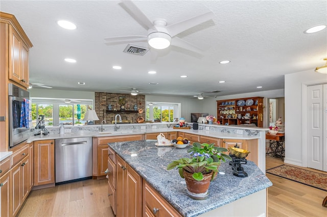 kitchen featuring visible vents, a center island, light wood-type flooring, appliances with stainless steel finishes, and a sink