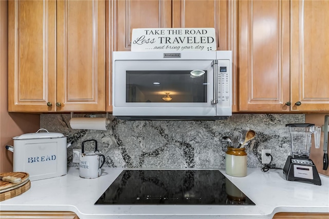 kitchen with black electric cooktop, light stone countertops, and tasteful backsplash