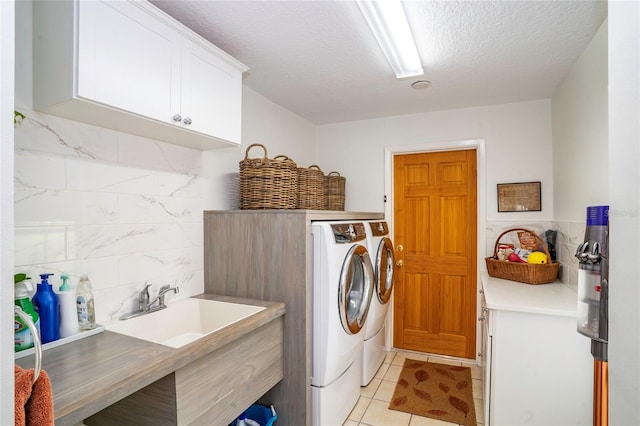 laundry room with cabinets, separate washer and dryer, a textured ceiling, light tile patterned floors, and tile walls