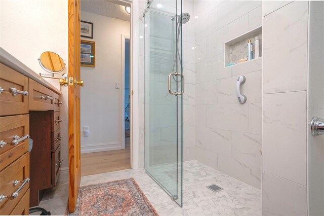 bathroom with a textured ceiling, an enclosed shower, and wood-type flooring