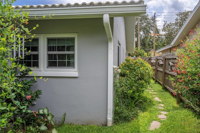 view of property exterior featuring stucco siding, a tile roof, and fence