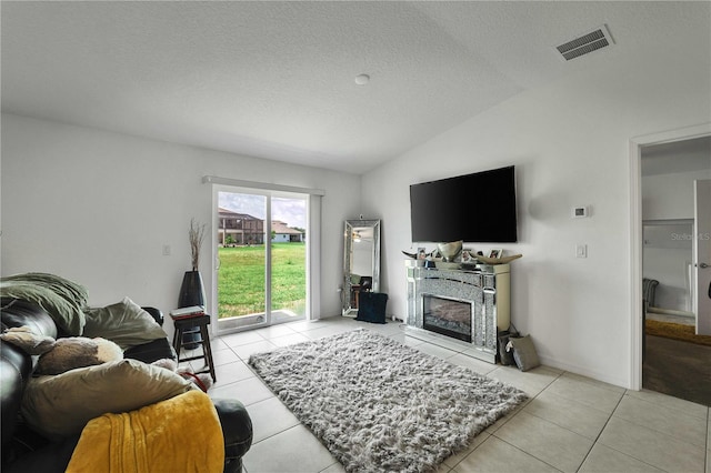 living room featuring vaulted ceiling, a textured ceiling, and light tile patterned floors