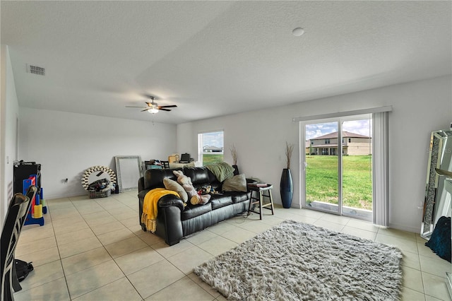 tiled living room with ceiling fan, a textured ceiling, and plenty of natural light