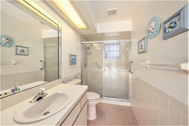 bathroom featuring tile patterned flooring, vanity, toilet, and a shower with shower door