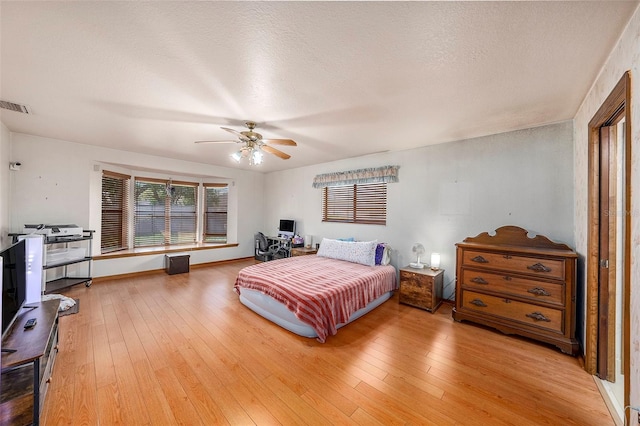 bedroom with ceiling fan, a textured ceiling, and light wood-type flooring