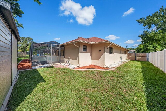 rear view of house featuring a lanai and a yard