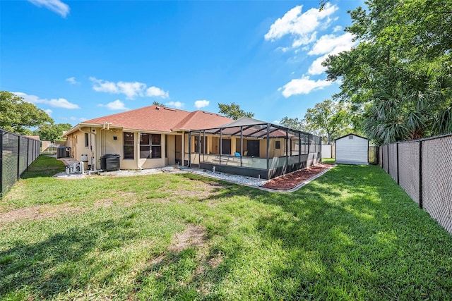 back of property featuring central air condition unit, glass enclosure, a yard, and a shed