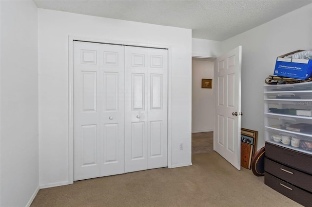 bedroom with light carpet, a textured ceiling, and a closet