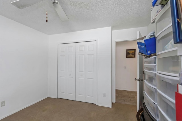 carpeted bedroom with a closet, a textured ceiling, and ceiling fan