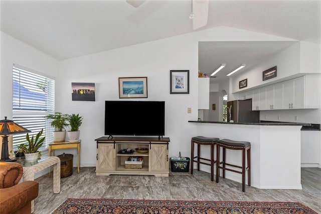 living room featuring light hardwood / wood-style floors, ceiling fan, and vaulted ceiling