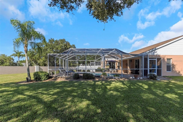 back of house with a lanai and a lawn