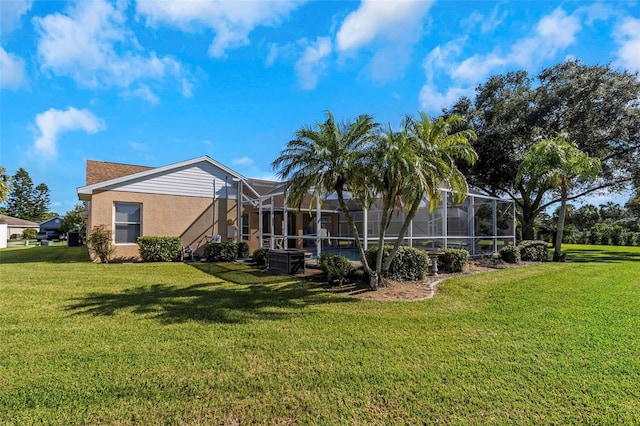 rear view of property featuring a lanai and a lawn