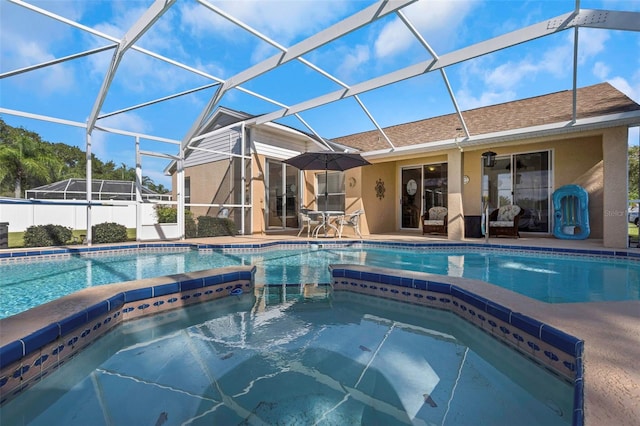 view of pool with a patio, an in ground hot tub, and glass enclosure