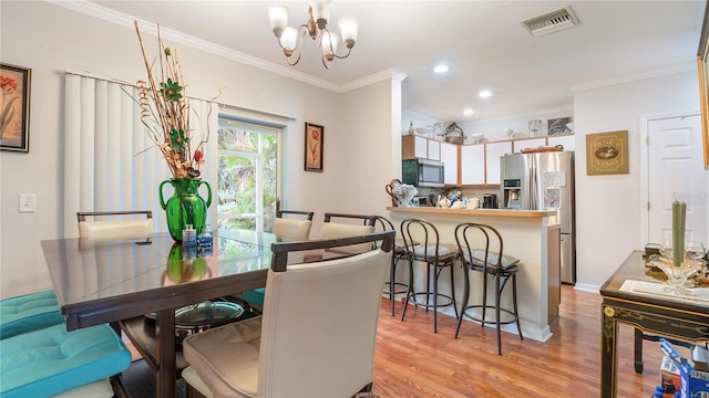 dining room with crown molding, light hardwood / wood-style flooring, and an inviting chandelier