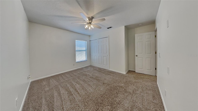 unfurnished bedroom with a textured ceiling, light colored carpet, ceiling fan, and a closet