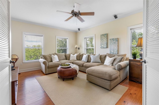 living area with baseboards, light wood-style flooring, ornamental molding, and a ceiling fan